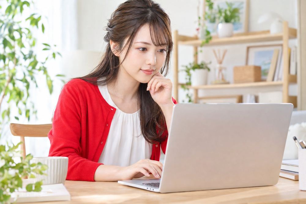 20代の女性がパソコンで配信のリプレイを再生し、背景に映っているものを一つずつ目で追って確かめている