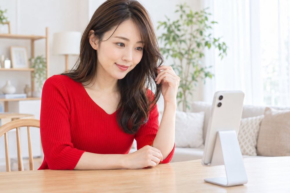 女性がスマホのビデオ通話で、画面の向こうの相手に映り方を相談している