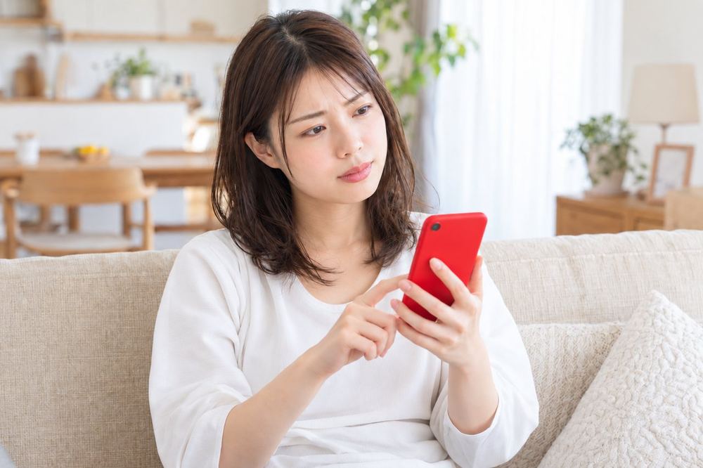 女性がソファでスマホの募集ページを読み、言葉の意味を調べている