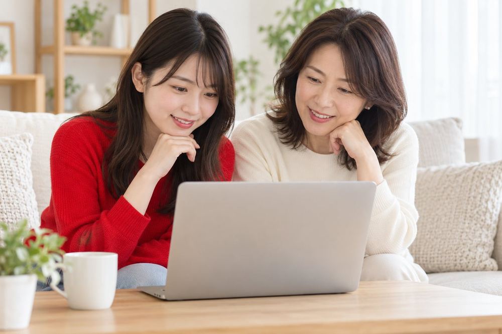 大学生くらいの女性が自宅のリビングで、母親と一緒に募集の内容を読んでいる