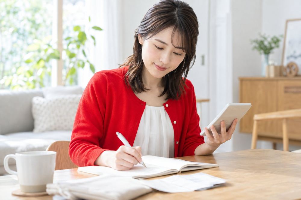 女性が電卓を手に、ノートに書いた計算式を見ながら、住民税の目安を計算している