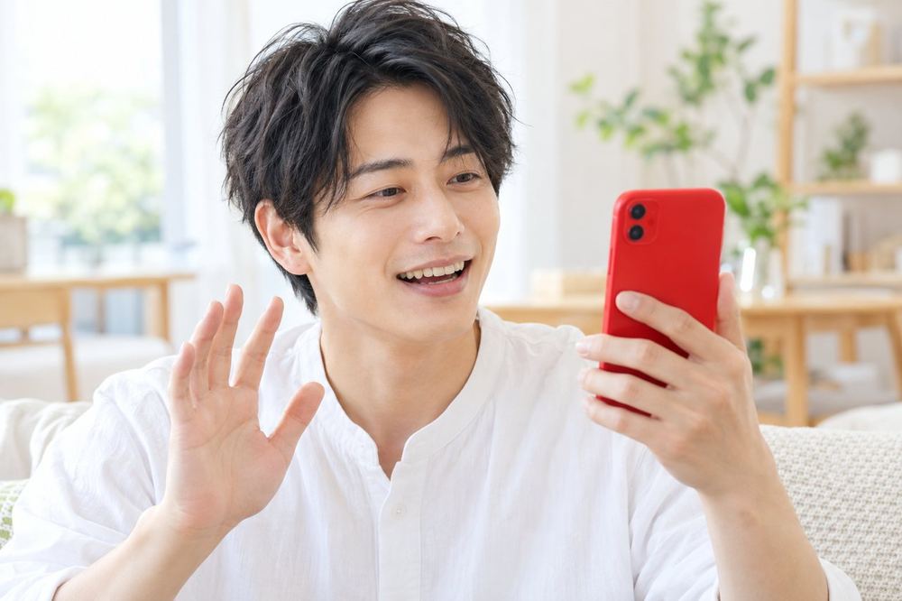 男性がスマホで配信の画面を見ながら、視聴者のコメントに笑顔で答えている
