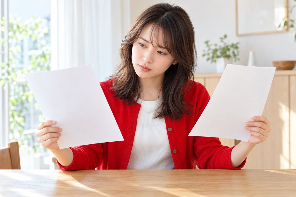 女性がテーブルで二枚の紙を見比べ、どちらの形で始めるかを考えている