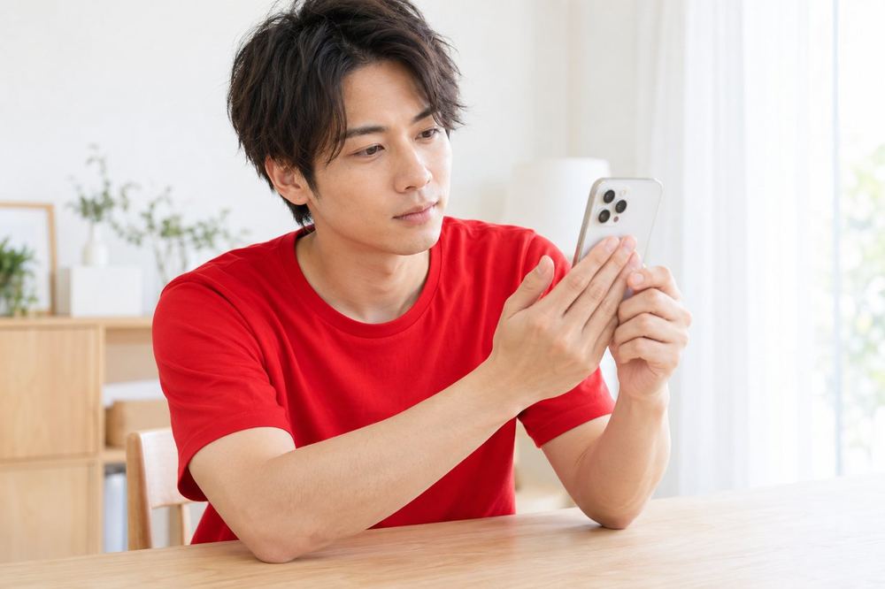 机の前で男性がスマホの背面に手をあて、配信中の熱の感じ方を確かめている
