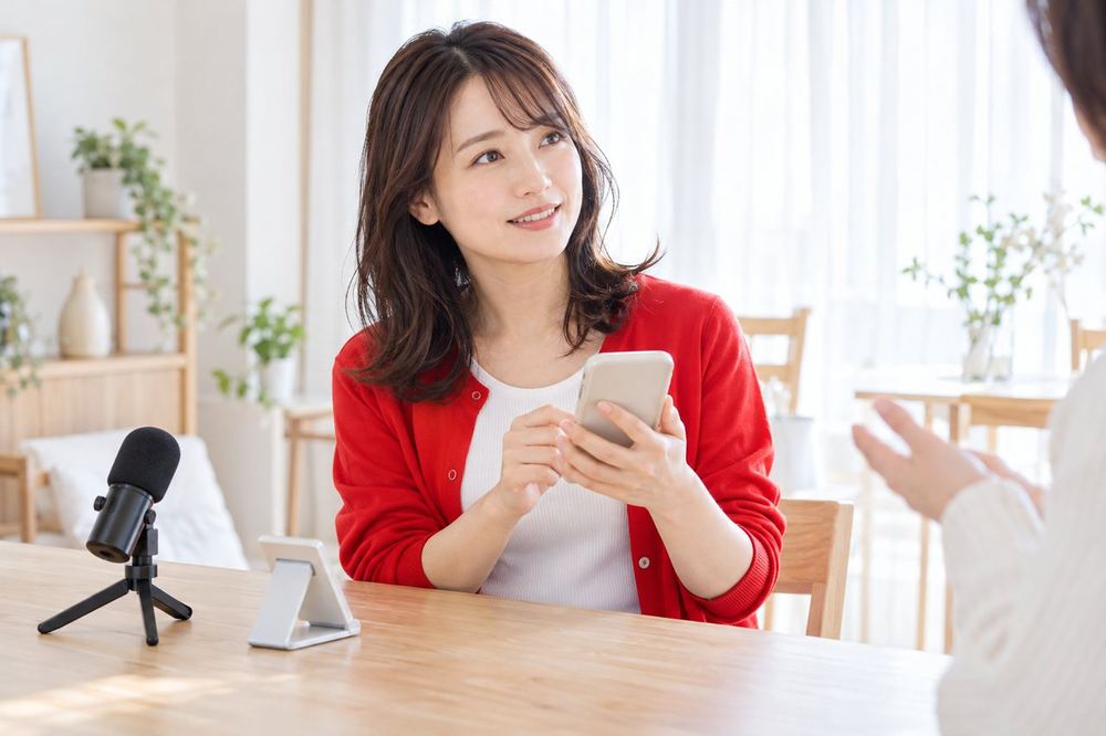 明るい部屋で、女性がスマホを手に持ち、部屋の映り方と機材について相談している
