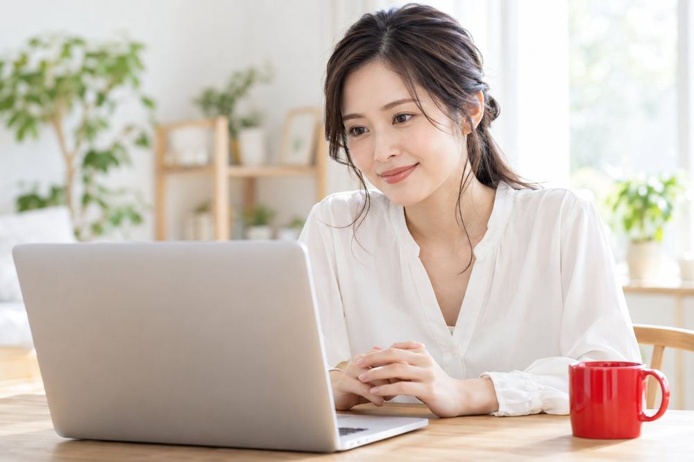 女性が自宅のデスクでノートパソコンに向かい、オンラインの面談で落ち着いて話を聞いている
