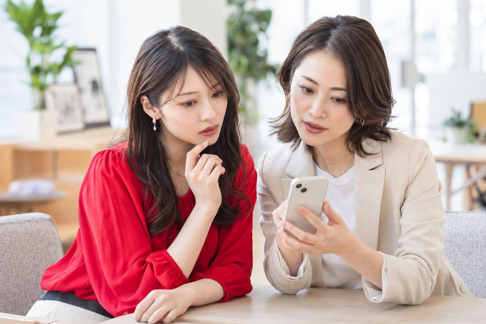 女性がマネージャーとスマホの画面を一緒に見ながら、届いた通知の内容を相談している