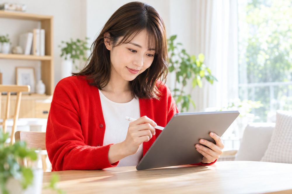 明るい部屋で、女性がタブレットにメモを取りながら、事務所の面談で聞くことを整理している