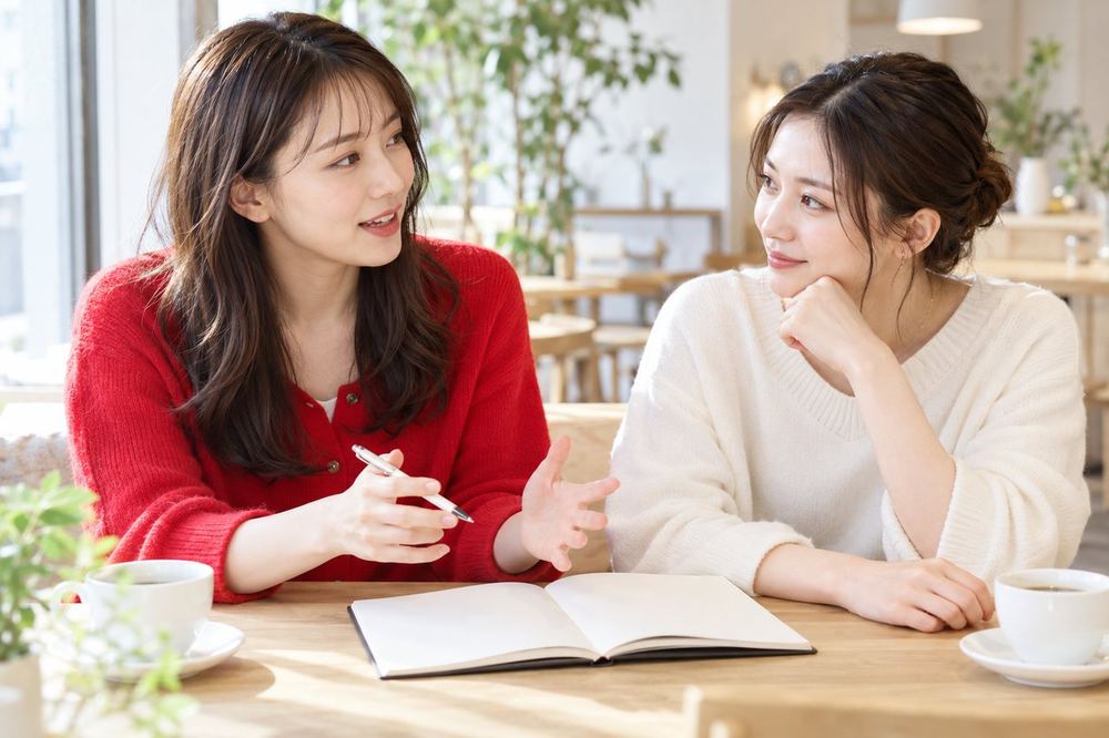 カフェで、女性ふたりがノートを広げ、コラボ配信で話す内容と順番を打ち合わせている