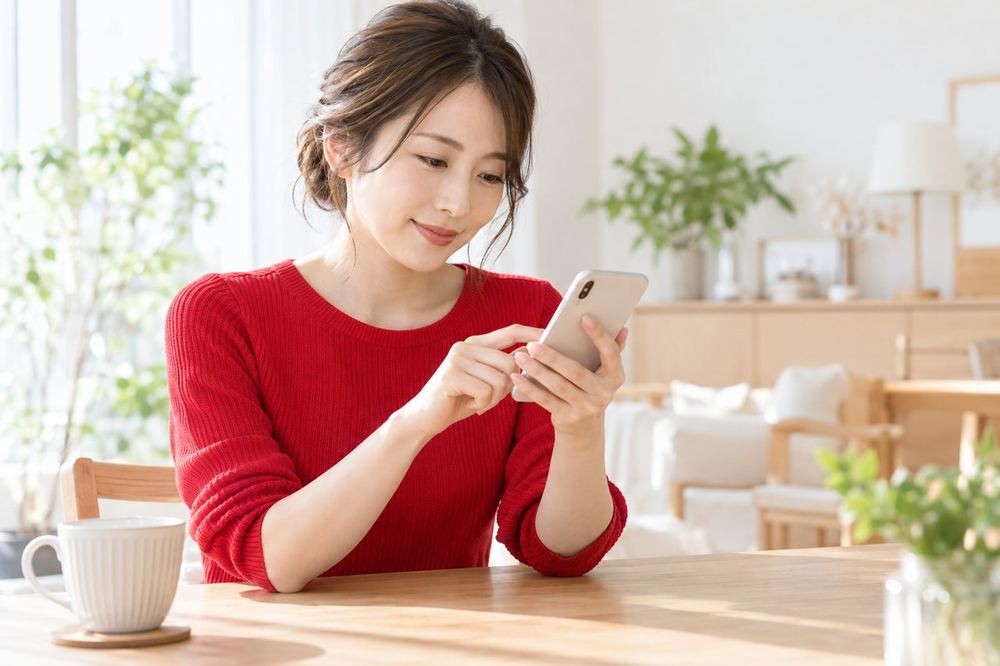 30代の女性が月初の朝にスマホのカレンダーを開き、今月の配信の予定を書き込んでいる