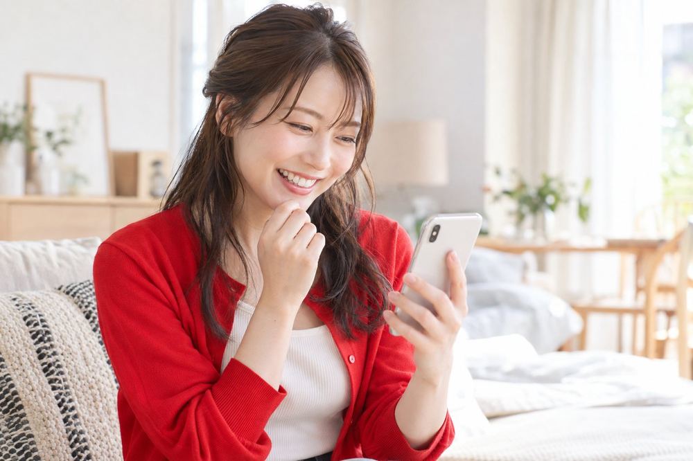 女性がスマホで、配信中に届いたギフトの表示を眺めて笑顔になっている