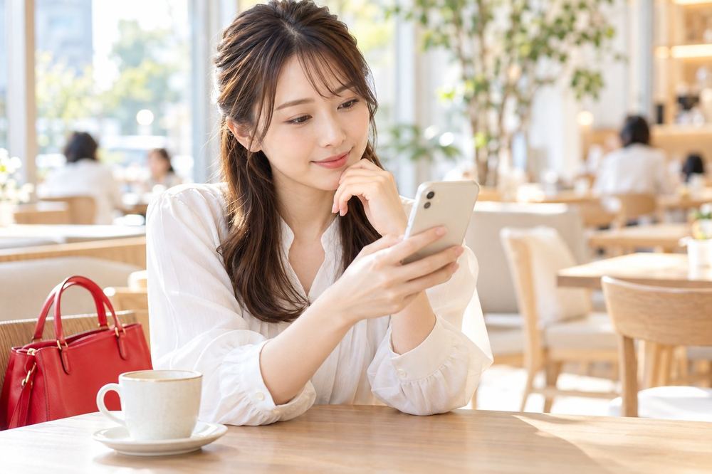 女性がカフェで、スマホを見ながら自分に向いている配信を考えている