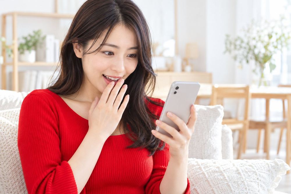 女性がスマホで、配信画面に表示されたギフトの演出を見て驚いている
